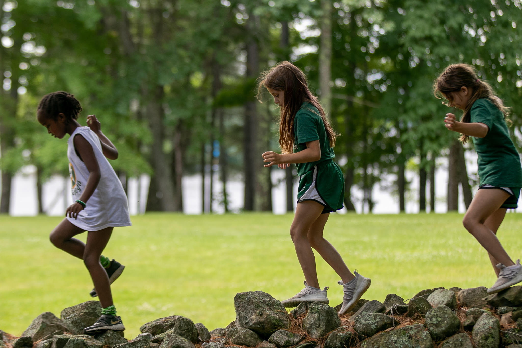 Three campers exploring a stone wall among the trees at Vega